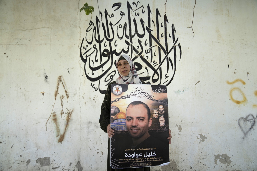 Palestinian Dalal Awawdeh poses with a poster of her husband Khalil Awawdeh, who is a prisoner in Israel, at the family house, in the West Bank village of Idna, Hebron, Tuesday, Aug. 9, 2022. Awawdeh, who is on a protracted hunger strike, was moved Thursday from an Israeli jail to a hospital because of his worsening condition, the prisoner's wife said.