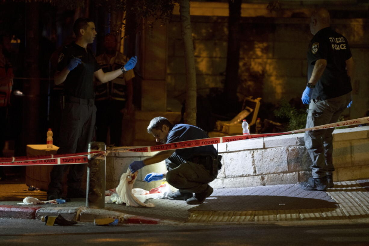 Israeli police crime scene investigators work at the scene of a shooting attack that wounded several Israelis near the Old City of Jerusalem, early Sunday, Aug. 14, 2022. Israeli police and medics say a gunman opened fire at a bus in a suspected Palestinian attack that came a week after violence flared up between Israel and militants in Gaza.
