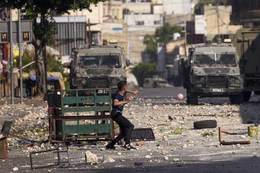 Palestinian demonstrators clash with the Israeli army while forces carry out an operation in the West Bank town of Nablus, Tuesday, Aug. 9, 2022. Israeli police said forces encircled the home of Ibrahim al-Nabulsi, who they say was wanted for a string of shootings in the West Bank earlier this year. They said al-Nabulsi and another Palestinian militant were killed in a shootout at the scene, and that troops found arms and explosives in his home.