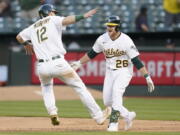 Oakland Athletics' Sheldon Neuse (26) is congratulated by Sean Murphy (12) after hitting into a fielder's choice that scored Tony Kemp during the 10th inning of a baseball game against the Seattle Mariners in Oakland, Calif., Saturday, Aug. 20, 2022.