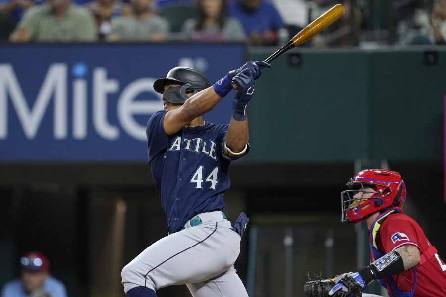 Seattle Mariners' Julio Rodriguez (44) follows through on a two-run single next to Texas Rangers catcher Jonah Heim during the fourth inning.
