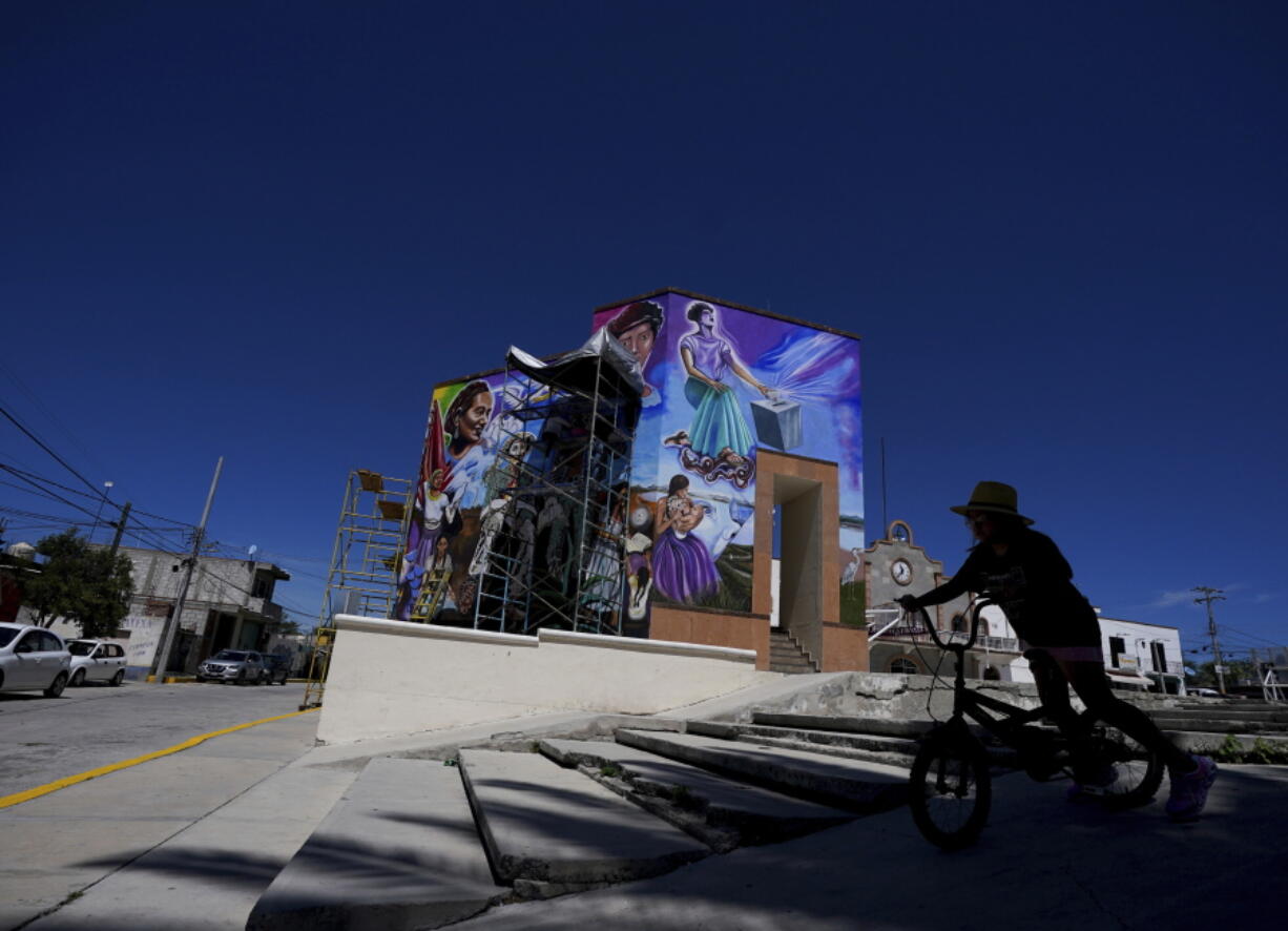 A bicyclist rides past a mural painted by Mexican artist Jesus Rodriguez Arevalo on July 30 in San Salvador, Mexico.