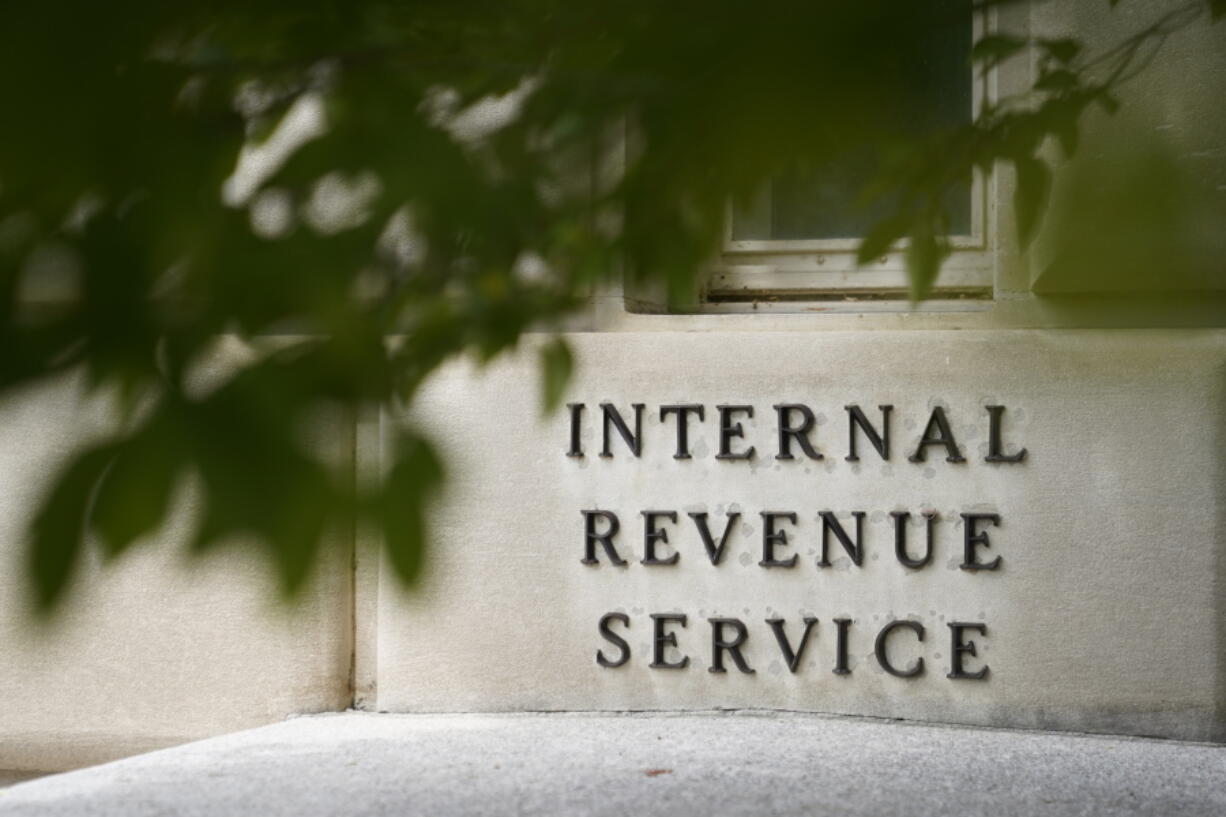 FILE - A sign is displayed outside the Internal Revenue Service building May 4, 2021, in Washington.  On Friday, Aug. 19, 2022, The Associated Press reported on stories circulating online incorrectly claiming an online job ad shows that all new employees that the IRS intends to hire after a funding boost in the Inflation Reduction Act will be required to carry a firearm and use deadly force if necessary.