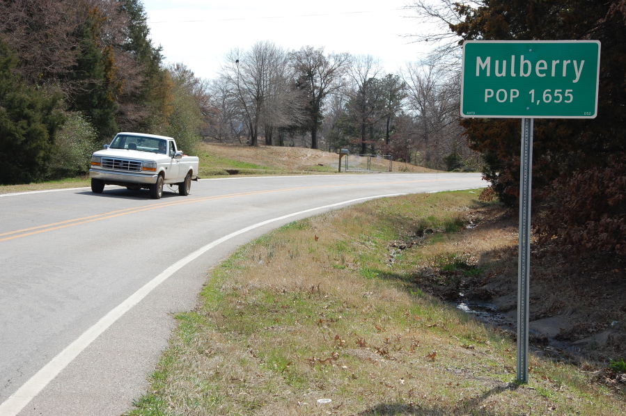 FILE - A truck drives near a population sign in Mulberry, Ark., on March 13, 2013. Three law enforcement officers in Arkansas have been suspended after a video posted on social media showed a suspect being held down on the ground and beaten by police. Arkansas State Police said Sunday, Aug. 21, 2022 that it would investigate the use of force by the officers earlier in the day outside a convenience store in Mulberry.