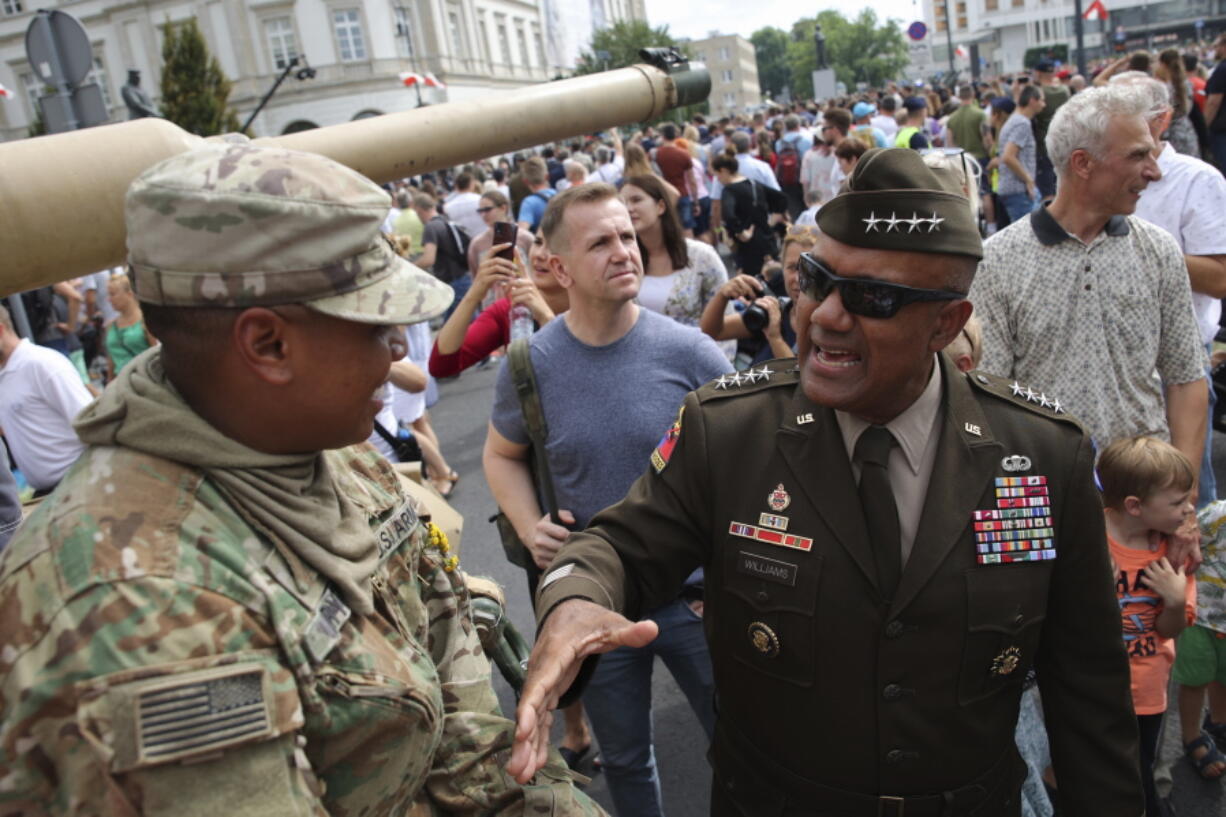 Gen. Darryl Williams, the new commanding general of United States Army Europe and Africa, second right, greets with US soldier during a picnic marking the Polish Army Day in Warsaw, Poland, Monday, Aug. 15, 2022. The Polish president and other officials marked their nation's Armed Forces Day holiday Monday alongside the U.S. army commander in Europe and regular American troops, a symbolic underlining of NATO support for members on the eastern front as Russia wages war nearby in Ukraine.