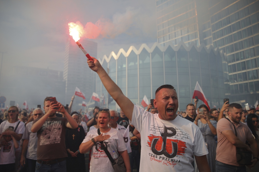 People stand on the city's main intersection holding national flags and flares to observe a minute of silence for the fighters and victims of the 1944 Warsaw Uprising against the Nazi German occupiers, in Warsaw, Poland, Monday Aug. 1, 2022. Poles are marking the 78th anniversary of the Warsaw Uprising, a doomed revolt against Nazi German forces during World War II.