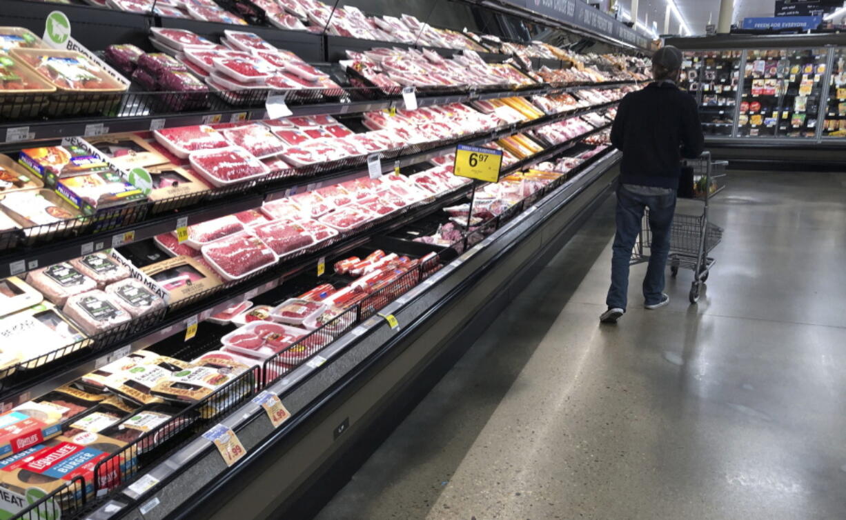 FILE - In this May 10, 2020 file photo, a shopper pushes his cart past a display of packaged meat in a grocery store in southeast Denver. Prices at the wholesale level fell from June to July, the first month-to-month drop in more than two years and a sign that some of the U.S. economy's inflationary pressures cooled last month. Thursday's report from the Labor Department showed that the producer price index -- which measures inflation before it reaches consumers -- declined 0.5% in July.