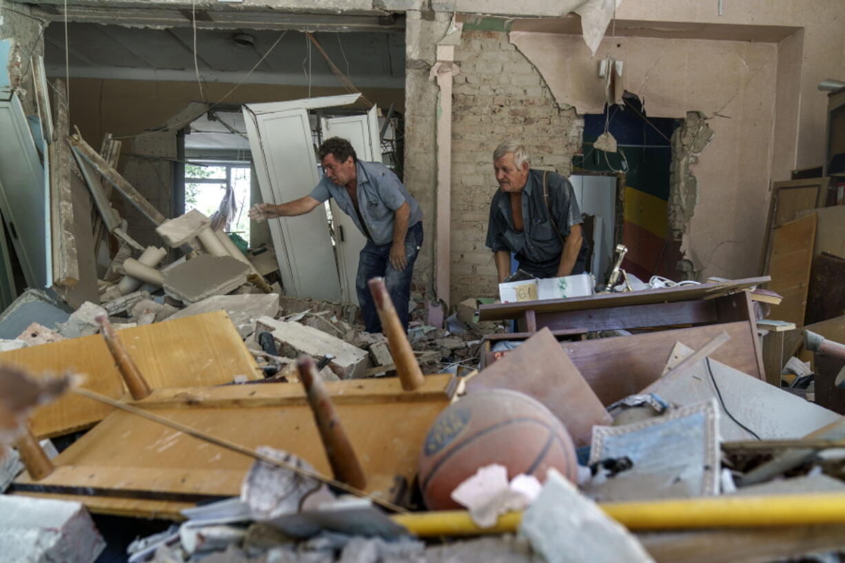Viktor Bielkin, left, and Anatolii Slobodianik, sift through the rubble of the Kramatorsk College of Technologies and Design, where they're maintenance workers, after it was hit in an early morning rocket attack in Kramatorsk, Donetsk region, eastern Ukraine, Friday, Aug. 19, 2022. Russia continued to shell towns and villages in Ukraine's embattled eastern Donetsk region, according to regional authorities, where Russian forces are pushing to overtake areas still held by Ukraine.