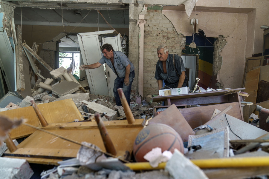 Viktor Bielkin, left, and Anatolii Slobodianik, sift through the rubble of the Kramatorsk College of Technologies and Design, where they're maintenance workers, after it was hit in an early morning rocket attack in Kramatorsk, Donetsk region, eastern Ukraine, Friday, Aug. 19, 2022. Russia continued to shell towns and villages in Ukraine's embattled eastern Donetsk region, according to regional authorities, where Russian forces are pushing to overtake areas still held by Ukraine.