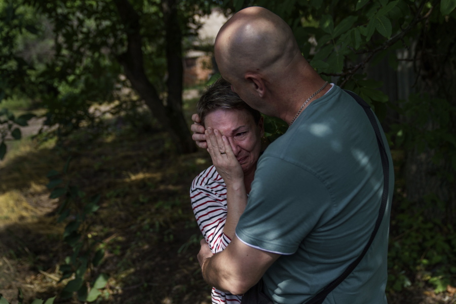 CORRECTS SPELLING TO VADIM NOT VADIN Marina Havrysh, left, is comforted by her husband, Vadim, as she weeps while watching her elderly parents helped into a van to be evacuated to a safer part of the country in the west from their home in Kramatorsk, Donetsk region, eastern Ukraine, Tuesday, Aug. 2, 2022. "I understand that this will be the last time I ever see them," she said.