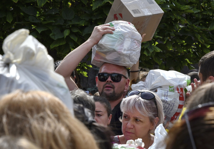 Local residents, many of whom fled the war, gather to hand out donated items such as medicines, clothes, and personal belongings to their relatives on the territories occupied by Russia, in Zaporizhzhia, Ukraine, Sunday, Aug. 14, 2022. Volunteers transport these items across the frontline and distribute them to addresses at their own risk.
