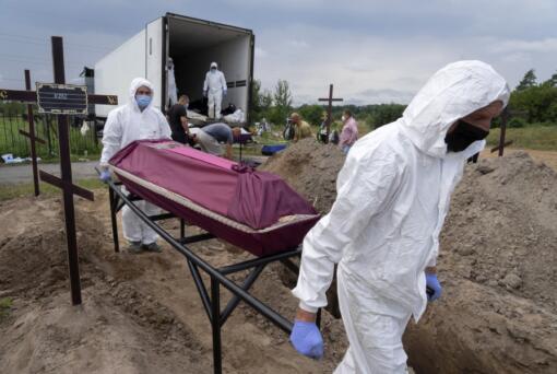 Workers carry a coffin with unidentified remains of a civilian murdered by the Russian troops during Russian occupation in Bucha, on the outskirts of Kyiv, Ukraine, Thursday, Aug. 11, 2022. Eleven unidentified bodies exhumed from a mass grave were buried in Bucha Thursday.