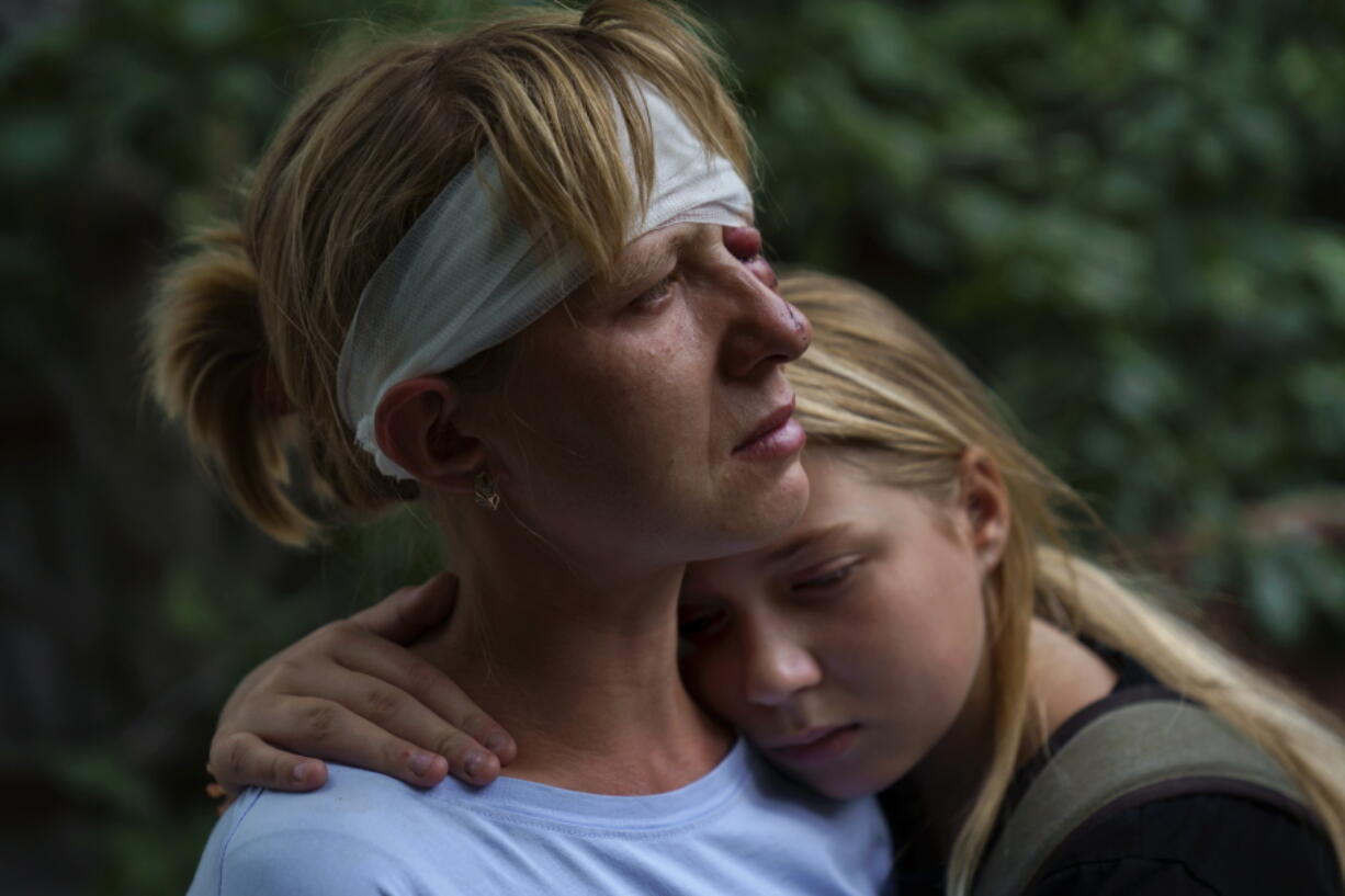 Nelia Fedorova, left, is embraced by her daughter, Yelyzaveta Gavenko, 11, as they visit a neighbor's home where someone was killed in a Russian rocket attack Friday night which also injured Federova, in Kramatorsk, Donetsk region, eastern Ukraine, Saturday, Aug. 13, 2022. The strike killed three people and wounded 13 others, according to the mayor.