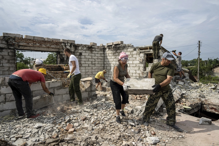 Volunteers clear rubble on the second floor of Zhanna and Serhiy Dynaeva's house which was destroyed by Russian bombardment, in a residential area, in the village of Novoselivka, near Chernihiv, Ukraine, Saturday, Aug. 13, 2022. Residents in many heavily-damaged areas in Ukraine have set up their own initiatives to rebuild homes before the winter as international organizations rush aid to Ukraine to help with the reconstruction effort.