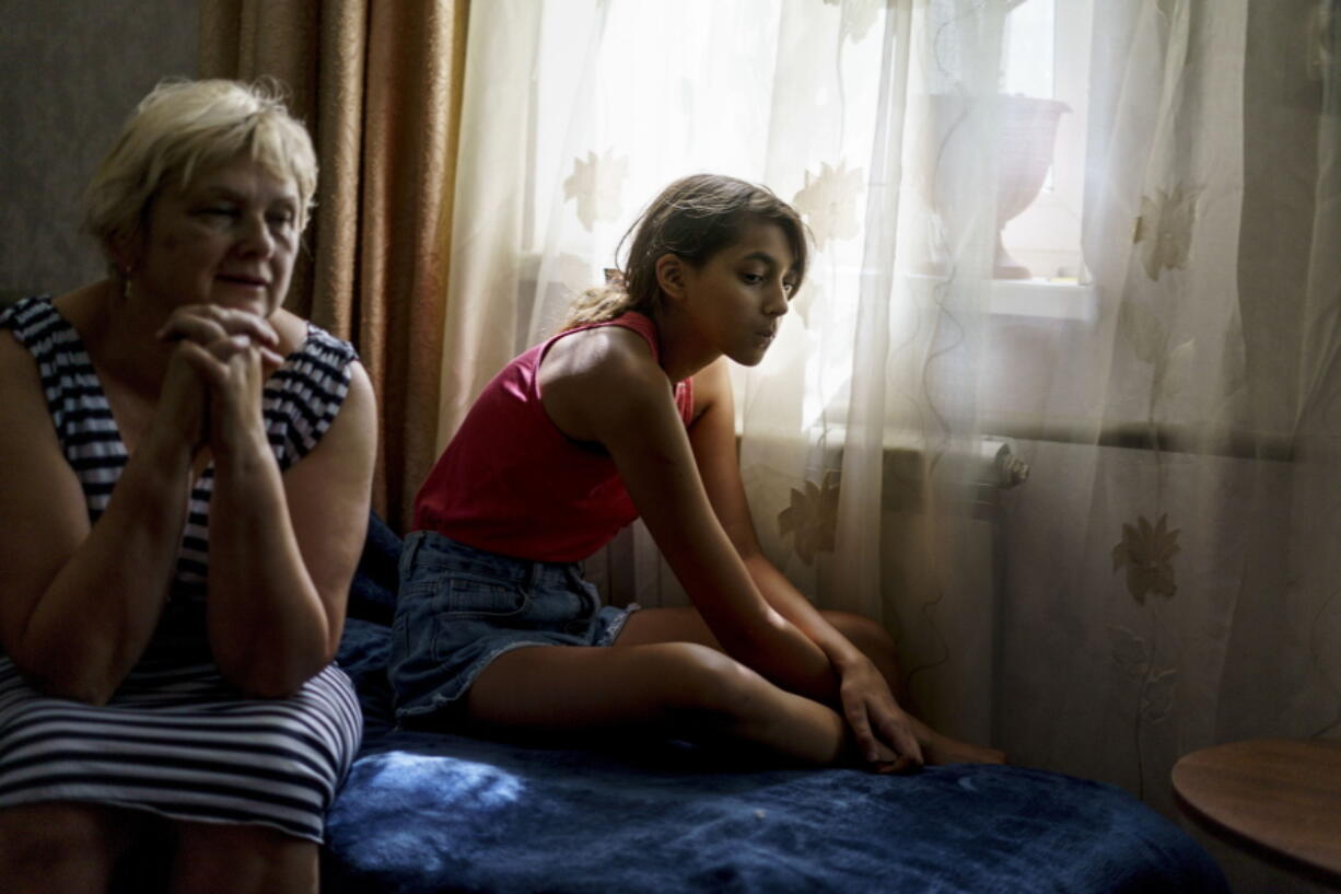 Anastasiia Aleksandrova, 12, right, sits with her grandmother, Olena, at their home in Sloviansk, Donetsk region, eastern Ukraine, Monday, Aug. 8, 2022. With cities largely emptied after hundreds of thousands have evacuated to safety, the young people that remain face alienation, loneliness and boredom as unlikely yet painful counterpoints to the fear and violence Moscow has unleashed on Ukraine.