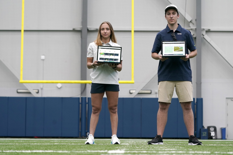 Becca Erenbaum, left, a senior football research analyst, and Peter Engler, a football research assistant, hold laptop computers as they pose for a photo on Aug. 3, 2022 at the Seattle Seahawks' NFL football indoor training facility in Renton, Wash. Coming off their worst season in head coach Pete Carroll's tenure, the Seahawks aimed to supplement their analytics staff -- that before this season was on the smaller side compared to other NFL teams -- with the hiring of Erenbaum and Engler, who will be called upon to take various data streams data and create a statistical analysis of situations. (AP Photo/Ted S. Warren) (Ted S.