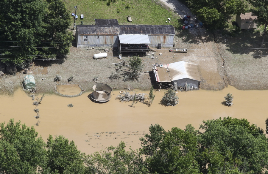 in this aerial photo, some homes in Breathitt County, Ky., are still surrounded by water on Saturday, July 30, 2022, after historic rains flooded many areas of Eastern Kentucky killing multiple people. A thin film of mud from the retreating waters covers many cars and homes.