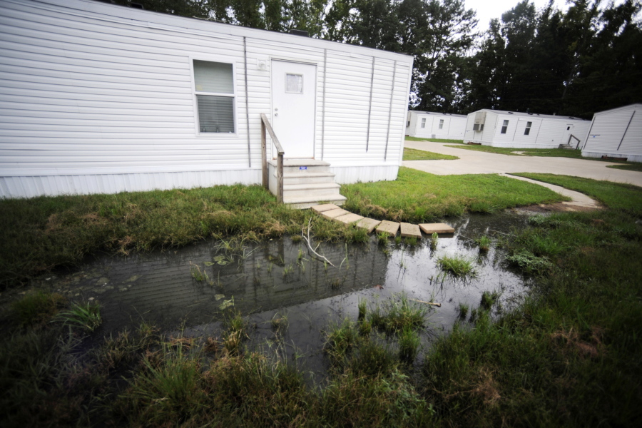 Fetid water stands outside a mobile home in a small mobile home park in rural Hayneville, Ala., on Monday, Aug. 1, 2022. The government announced a pilot program on Tuesday to help rural communities that face serious sewage problems like those in Lowndes County, where Hayneville is located.