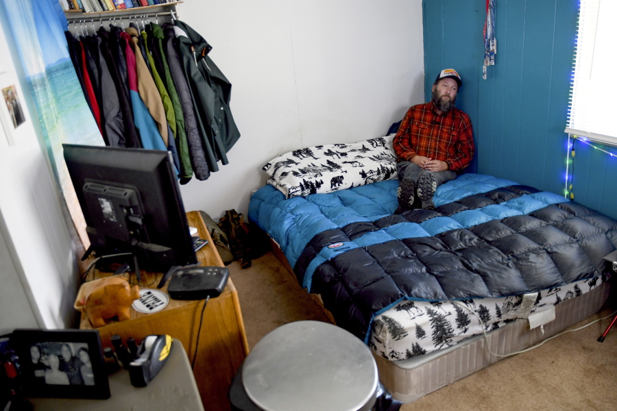 Sean Bailey sits in his bedroom, Thursday, Aug. 4, 2022, in Steamboat Springs, Colo. Bailey, who moved to Steamboat Springs in 2019, has been on a waitlist for three years to get one of Steamboat's affordable housing apartments. He says the 12-foot-by-12-foot space serves as his living room, dining room, den and office.