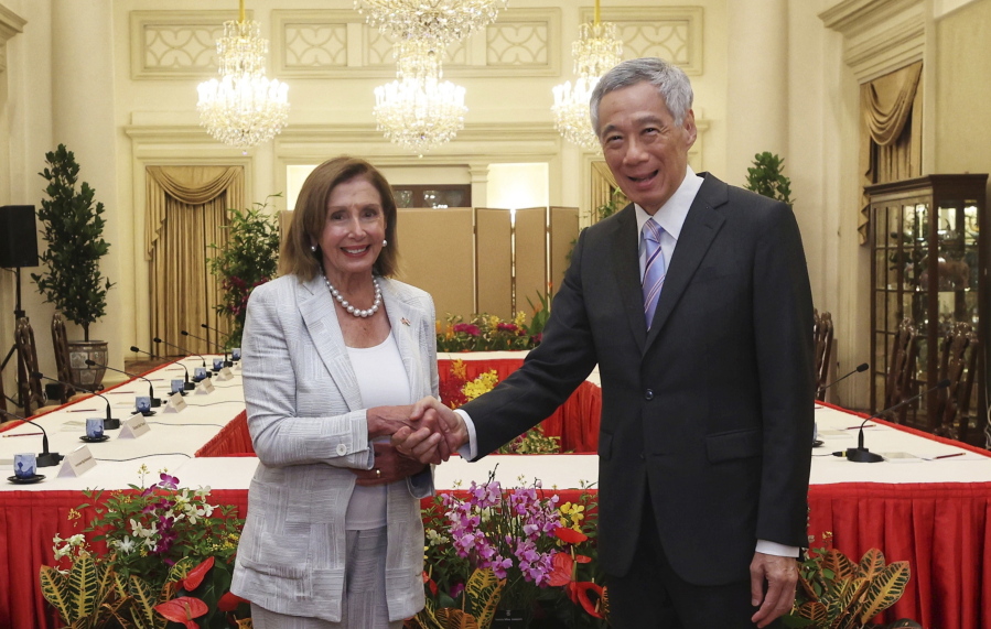 In this photo provided by Ministry of Communications and Information, Singapore, U.S. House Speaker Nancy Pelosi, left, and Prime Minister Lee Hsien Loong shake hands at the Istana Presidential Palace in Singapore, Monday, Aug. 1, 2022. Pelosi arrived in Singapore early Monday, kicking off her Asian tour as questions swirled over a possible stop in Taiwan that has fueled tension with Beijing.