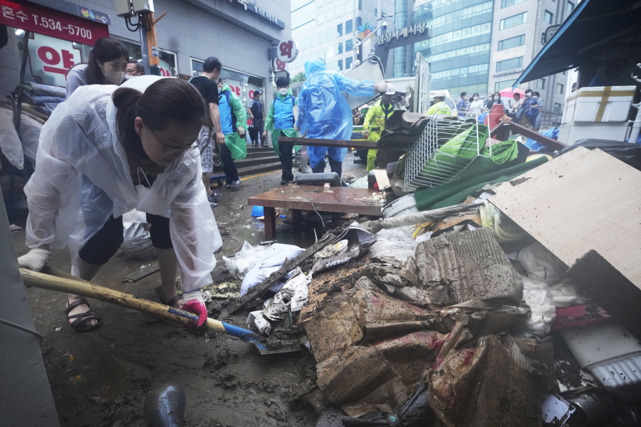 A woman cleans up debris after the water drained from a submerged traditional market following heavy rainfall in Seoul, South Korea, Tuesday, Aug. 9, 2022. Heavy rains drenched South Korea's capital region, turning the streets of Seoul's affluent Gangnam district into a river, leaving submerged vehicles and overwhelming public transport systems.