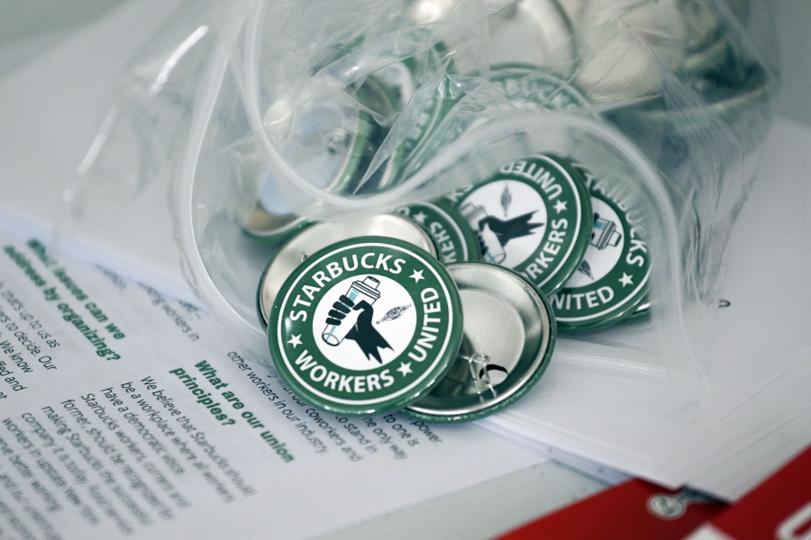 FILE -- Pro-union pins sit on a table during a watch party for Starbucks' employees union election, Dec. 9, 2021, in Buffalo, N.Y. Starbucks is asking the National Labor Relations Board to temporarily suspend all union elections at its U.S. stores in response to allegations of improper coordination between regional NLRB officials and the union.