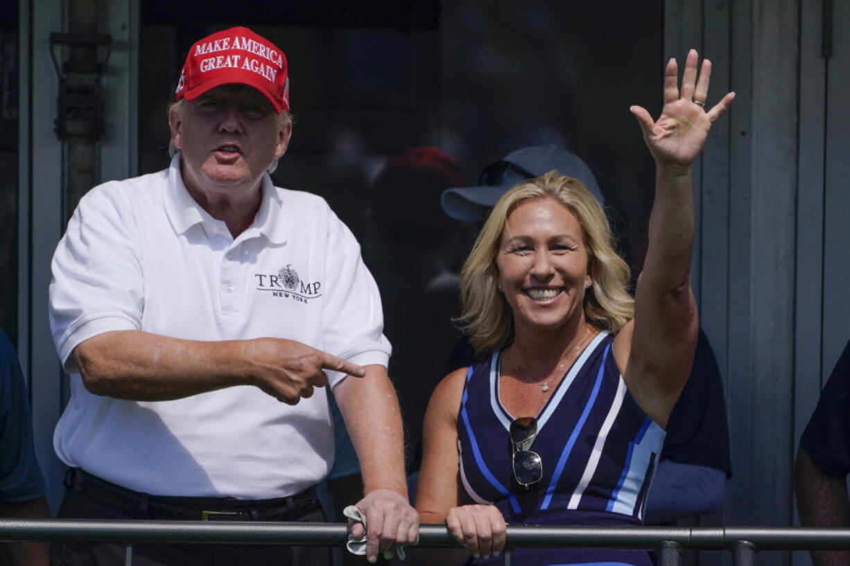 FILE - Rep. Marjorie Taylor Greene, R-Ga., waves while former President Donald Trump points to her while they look over the 16th tee during the second round of the Bedminster Invitational LIV Golf tournament in Bedminster, N.J., July 30, 2022. Republicans ranging from Senate Minority Leader Mitch McConnell to Marjorie Taylor Greene defended Trump against an unprecedented FBI search.