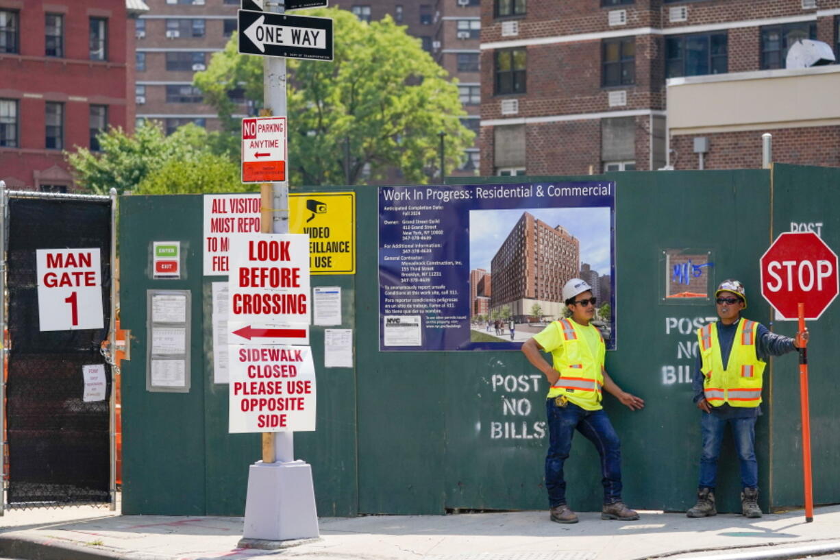 Construction workers help direct traffic outside a residential and commercial building under construction at the Essex Crossing development on the Lower East Side of Manhattan, Thursday, Aug. 4, 2022.  America's hiring boom continued last month as employers added a surprising 528,000 jobs despite raging inflation and rising anxiety about a recession.