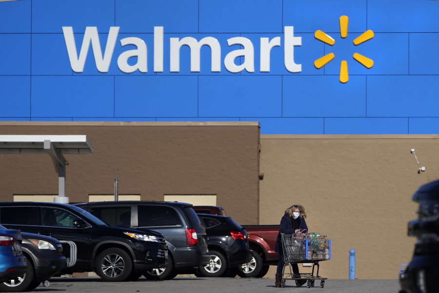 FILE - A woman wheels a cart with her purchases out of a Walmart, on Nov. 18, 2020, in Derry, N.H. Walmart, the nation's largest employer, is expanding its abortion coverage for employees, according to a memo sent to employees Friday, Aug. 19, 2022, after staying mum on the topic for months following the Supreme Court ruling that scrapped a nationwide right to abortion.