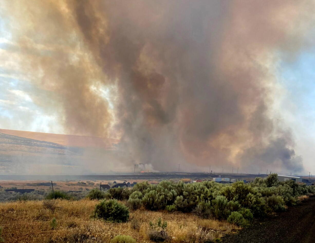 This photo provided by the Washington State Department of Transportation shows smoke from a wildfire burning south of Lind, Wash. on Thursday, Aug. 4, 2022. Sheriff's officials are telling residents in the town of Lind in eastern Washington to evacuate because of a growing wildfire south of town that was burning homes.