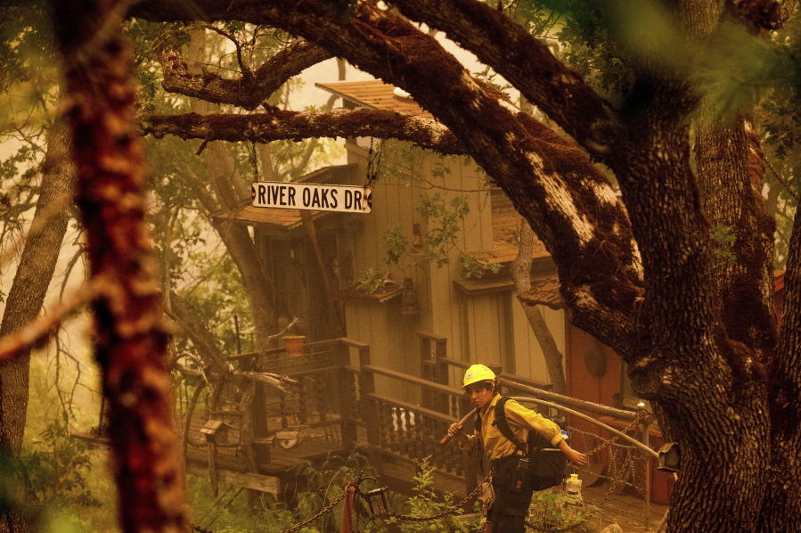 A firefighter battling the McKinney Fire protects a cabin in Klamath National Forest, Calif., on Sunday, July 31, 2022.