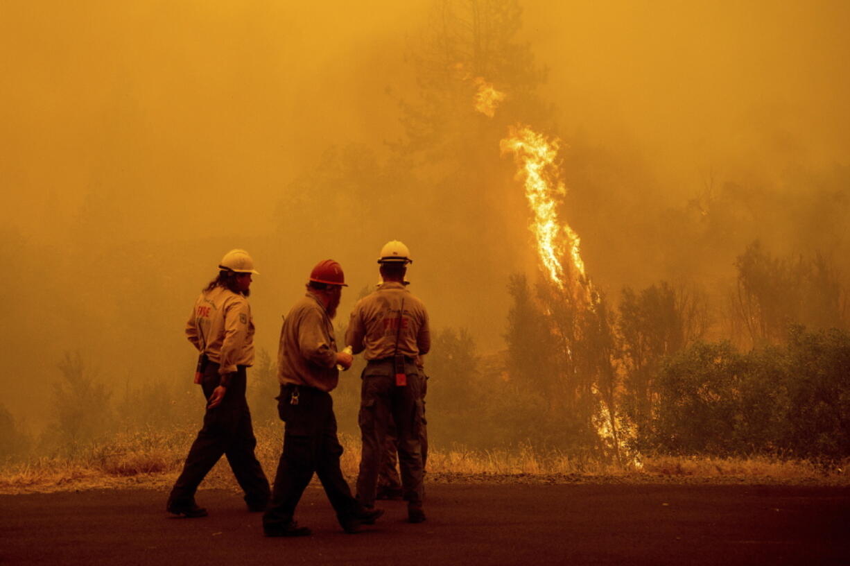 Flames from the McKinney Fire burn beyond firefighters in Klamath National Forest, Calif., on Sunday, July 31, 2022.