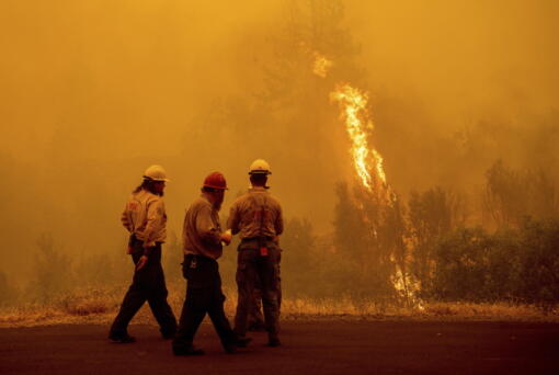 Flames from the McKinney Fire burn beyond firefighters in Klamath National Forest, Calif., on Sunday, July 31, 2022.