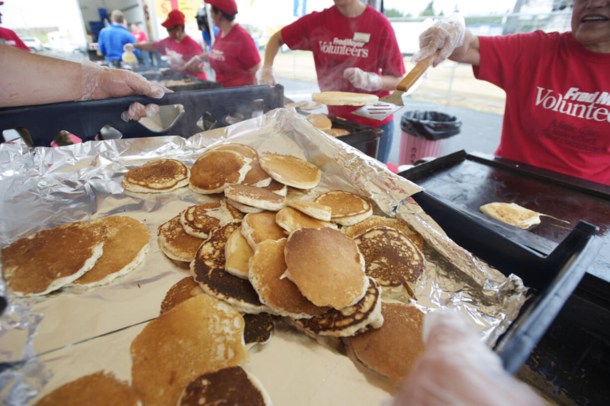 Fred Meyer volunteers cook and serve thousands of pancakes during the annual free pancake breakfast on opening day of the Clark County Fair.
