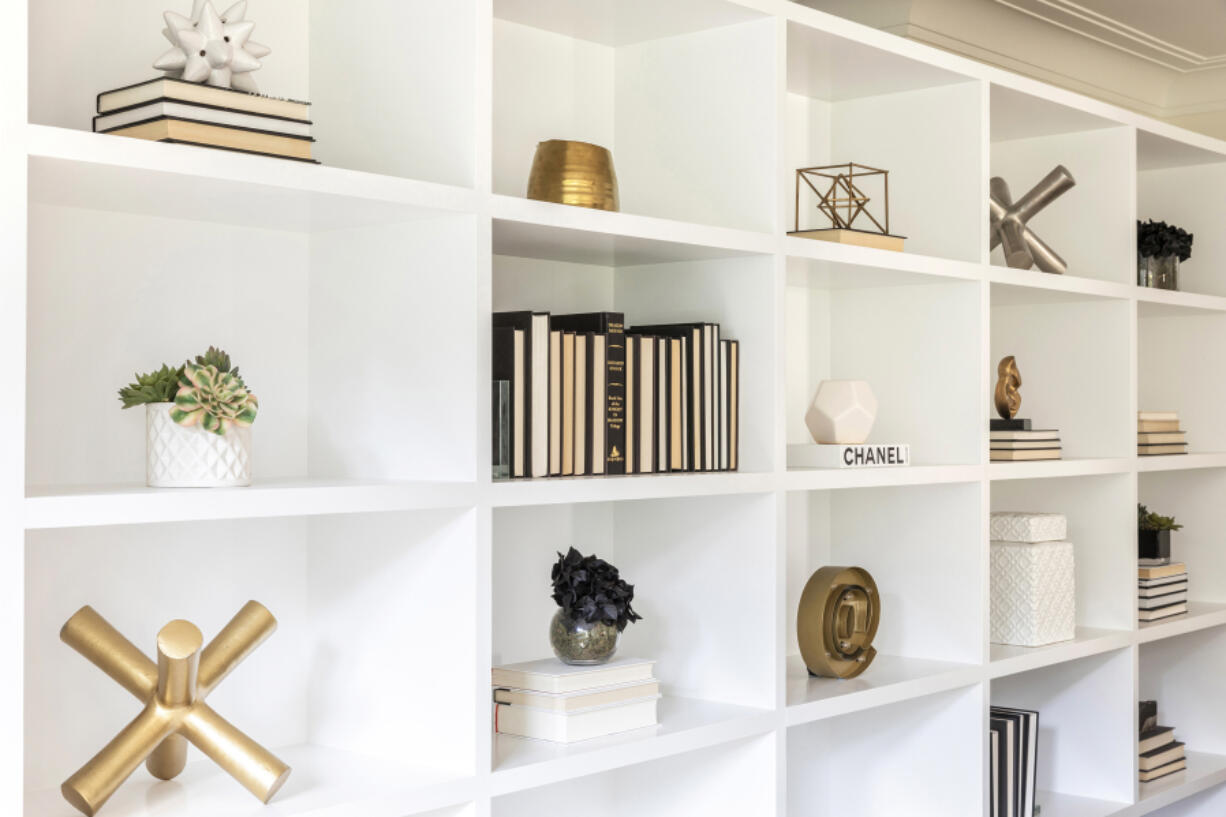 A minimal color palette of black and white, paired with brass accents, creates appealing decor vignettes on this bookcase.