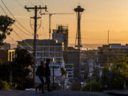 Two people walk along Bellevue Avenue while the sun sets in Capitol Hill on Thursday, April 22, 2021, in Seattle.