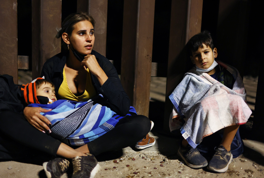 An immigrant mother from Cuba sits with her sons after crossing the border from Mexico, as they await processing by the U.S. Border Patrol, on May 19, 2022, in Yuma, Arizona.
