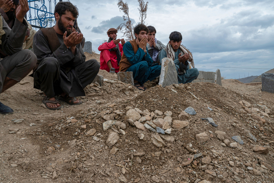 Afghans pray at a grave of victims, after burial ceremony in a cemetery on the outskirts of Kabul on Aug. 18, 2022.