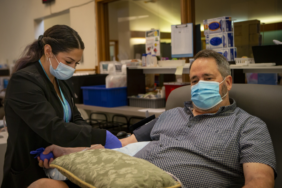 Dan Ertel looks away as blood collection specialist Marty Ortiz inserts a needle for Ertel's 500th platelet donation at Lane Bloodworks in Eugene, Ore., on Aug. 31.
