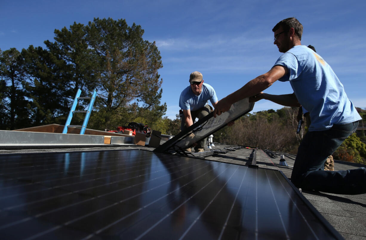 SolarCraft workers install a solar panel on the roof of a home in February 2015 in San Rafael, California. Renewable energy production is growing too slowly to solve the world's carbon emission problem, says historian Vaclav Smil.
