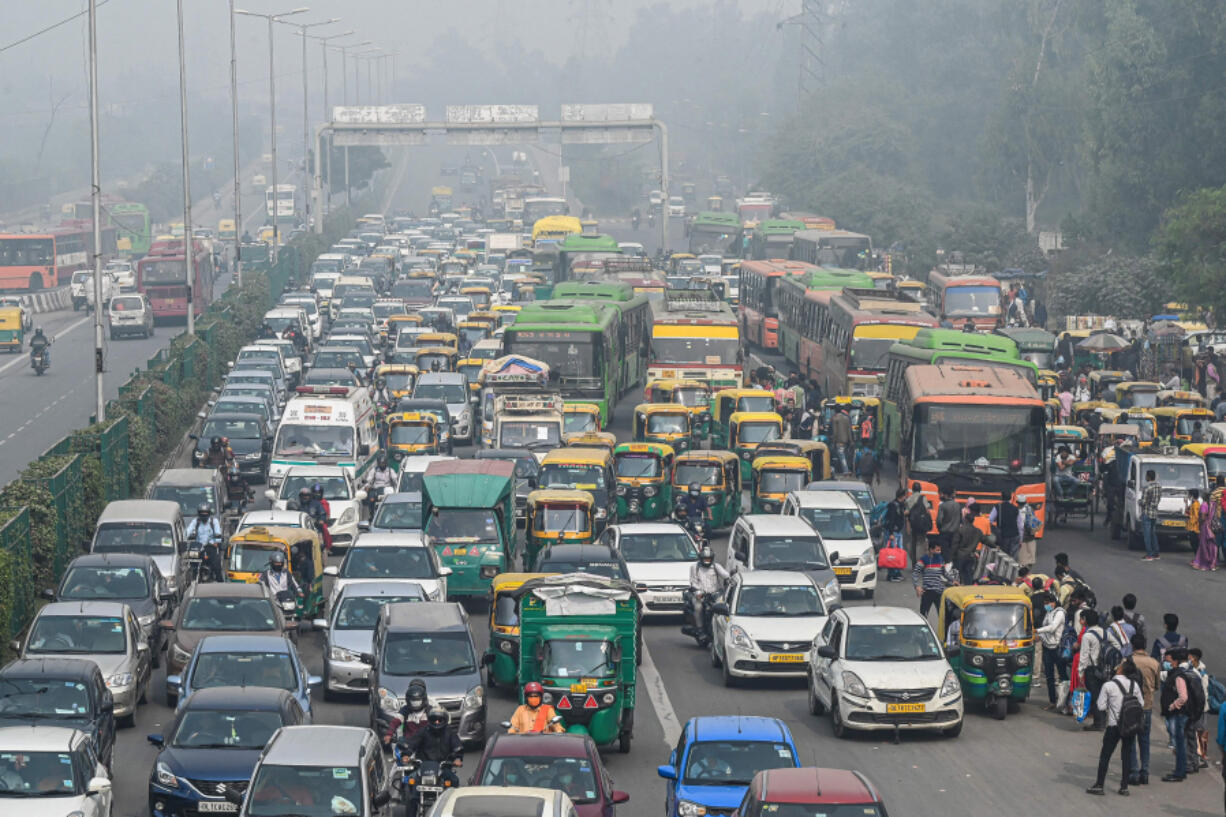 Commuters make their way along a busy road under heavy smoggy conditions in New Delhi on November 12, 2021.