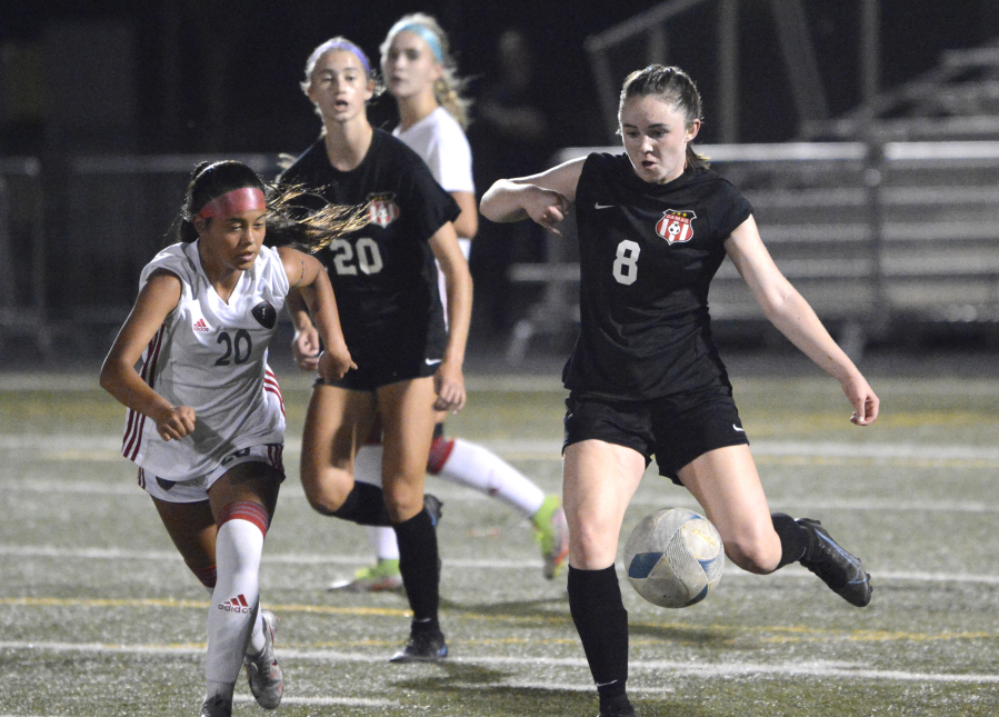 Nora Melcher, right, of Camas flips a pass ahead to a teammate while being defended by Union's Ohu Miles on Tuesday at Doc Harris Stadium in Camas.