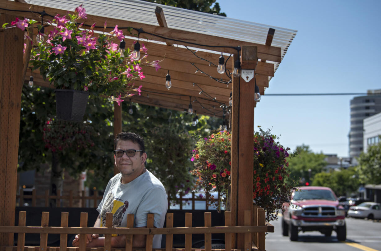 Elements owner Miguel Sosa takes a break in his restaurant's parklet on Main Street. The parklet is something that could be lost if the city decides to take away parking to make wider sidewalks.