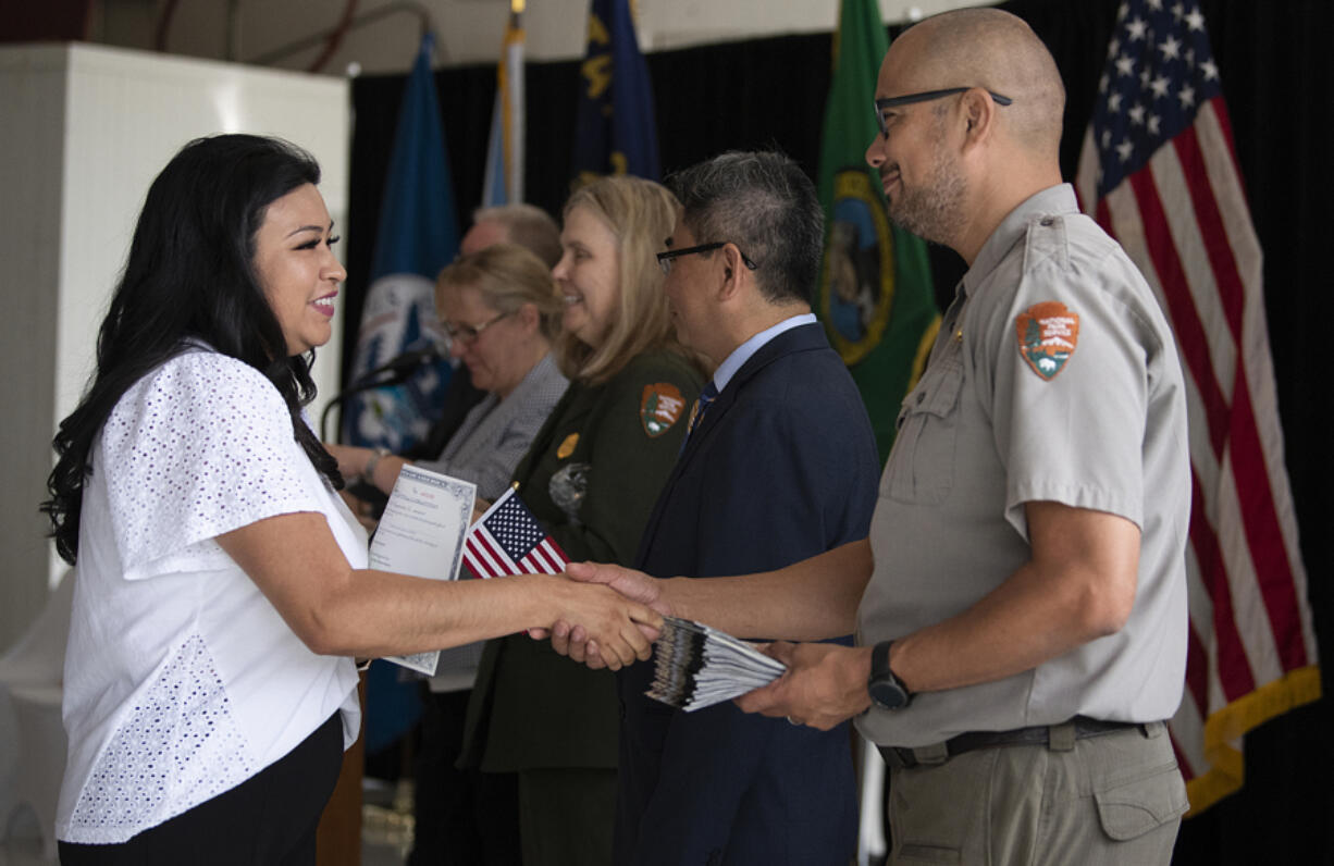 Victoria Prado, left, greets Aaron Ochoa, right, of Fort Vancouver National Historic Site, and others while celebrating her citizenship at Pearson Air Museum Historic Hangar on Thursday morning. Prado was one of 40 new U.S. citizens who participated in a naturalization ceremony at Fort Vancouver.