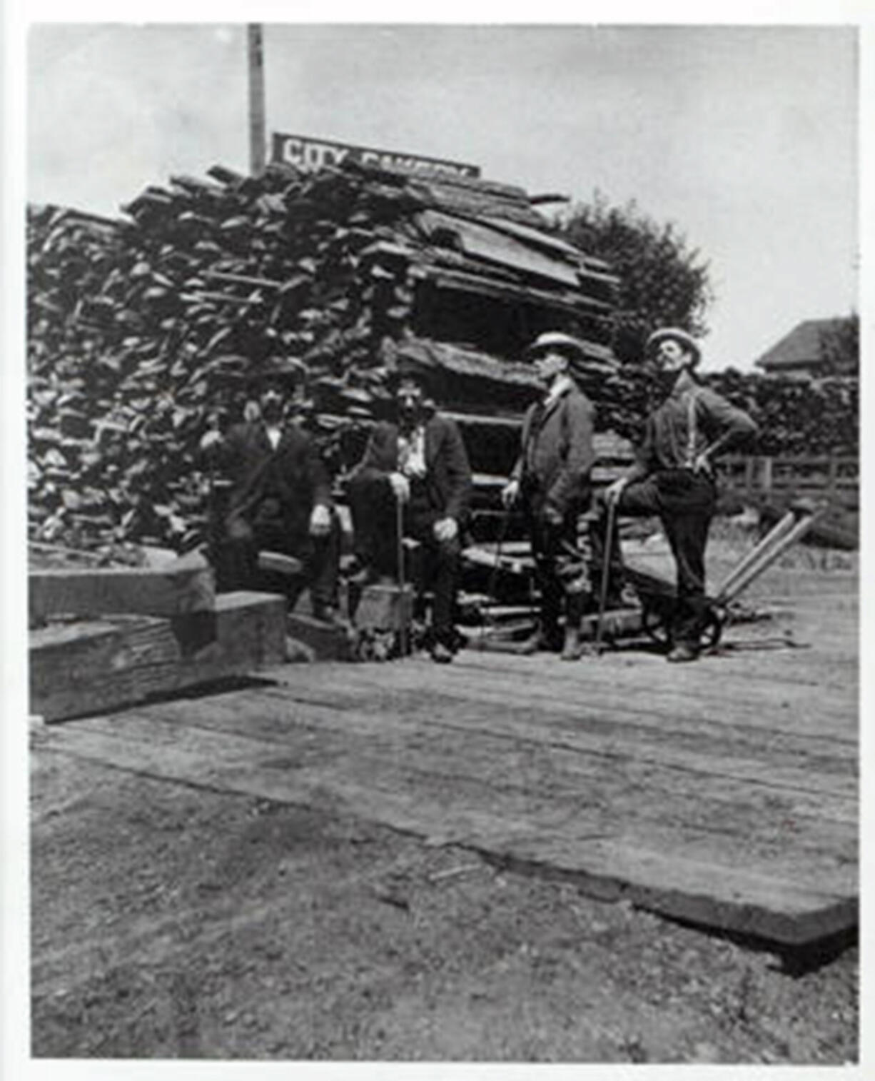 Vancouver was losing money on its first electricity generation plant when Joe Harvey offered to buy it in 1901 and run it as a regulated private utility company. He stands second from the right wearing a suit. On his right stands his older brother with a foot on the woodpile. As the Vancouver Electric Light and Power Company, they turned untold cords of wood into electricity to light the city.