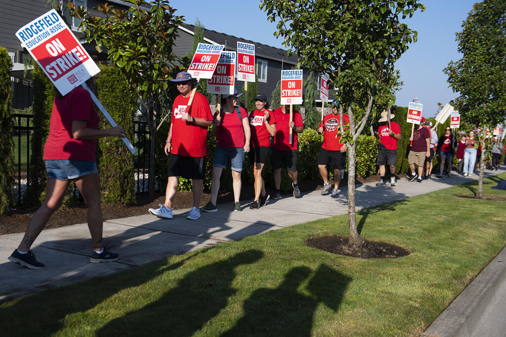 Early morning light casts the shadow of picketers as union members and community members gather to strike outside Ridgefield High School after a deal has not been reached between the teachers union and school officials despite working without a contract since Sep. 1, as seen Friday morning, Sept. 9, 2022.