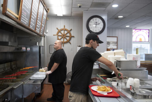 Crew members Stephen Landry, left, and Roman Rico work behind the front counter during the lunch rush at the Hazel Dell Skippers.