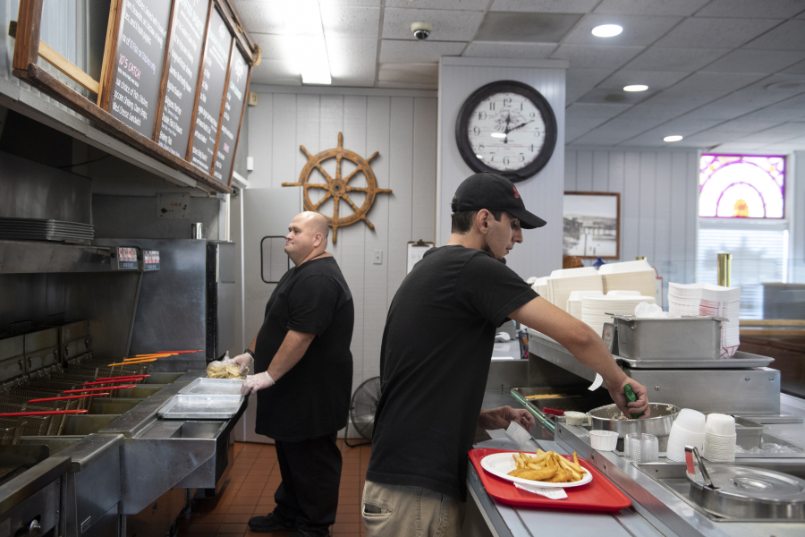 Crew members Stephen Landry, left, and Roman Rico work behind the front counter during the lunch rush at the Hazel Dell Skippers.