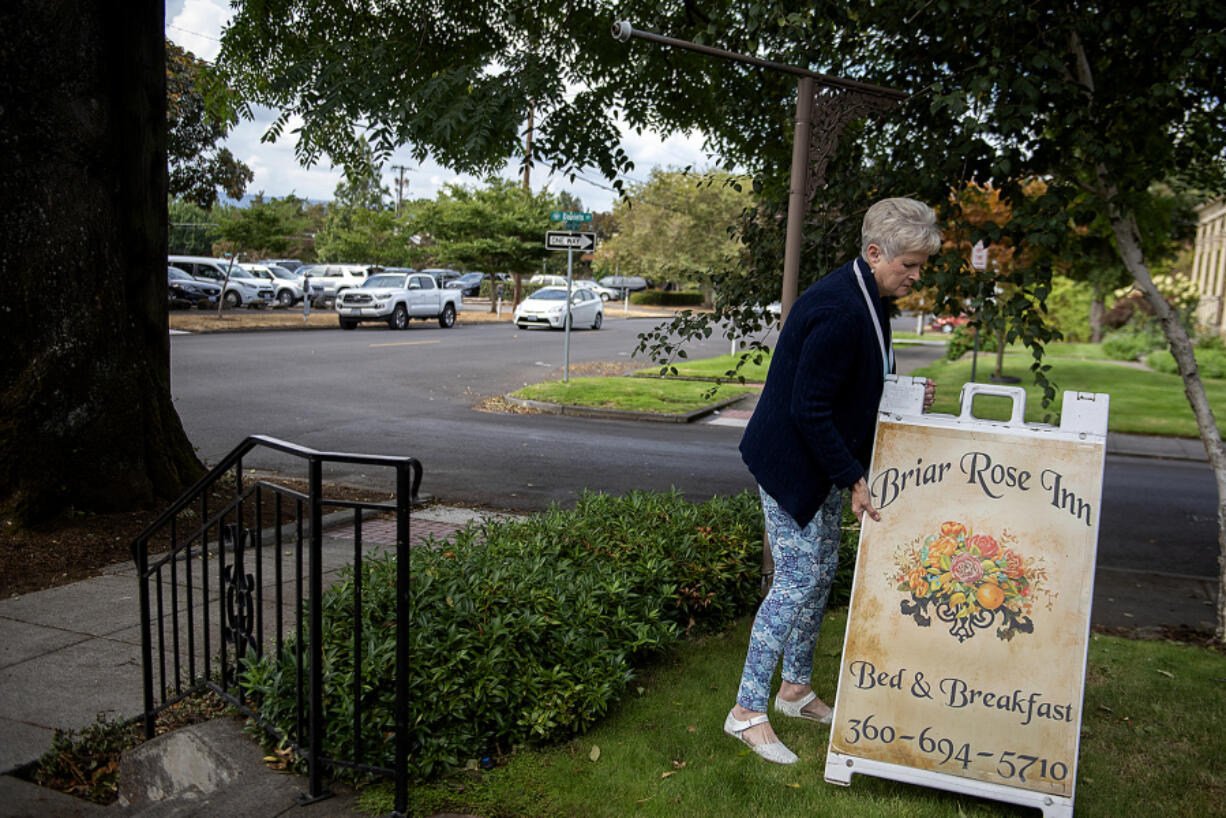 Sallie Reavey, co-owner of the Briar Rose Inn, adjusts a sign for her bed and breakfast Wednesday. She says she might have to sell the inn if a Safe Stay Community is established across the street.