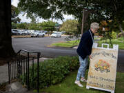 Sallie Reavey, co-owner of the Briar Rose Inn, adjusts a sign for her bed and breakfast Wednesday. She says she might have to sell the inn if a Safe Stay Community is established across the street.